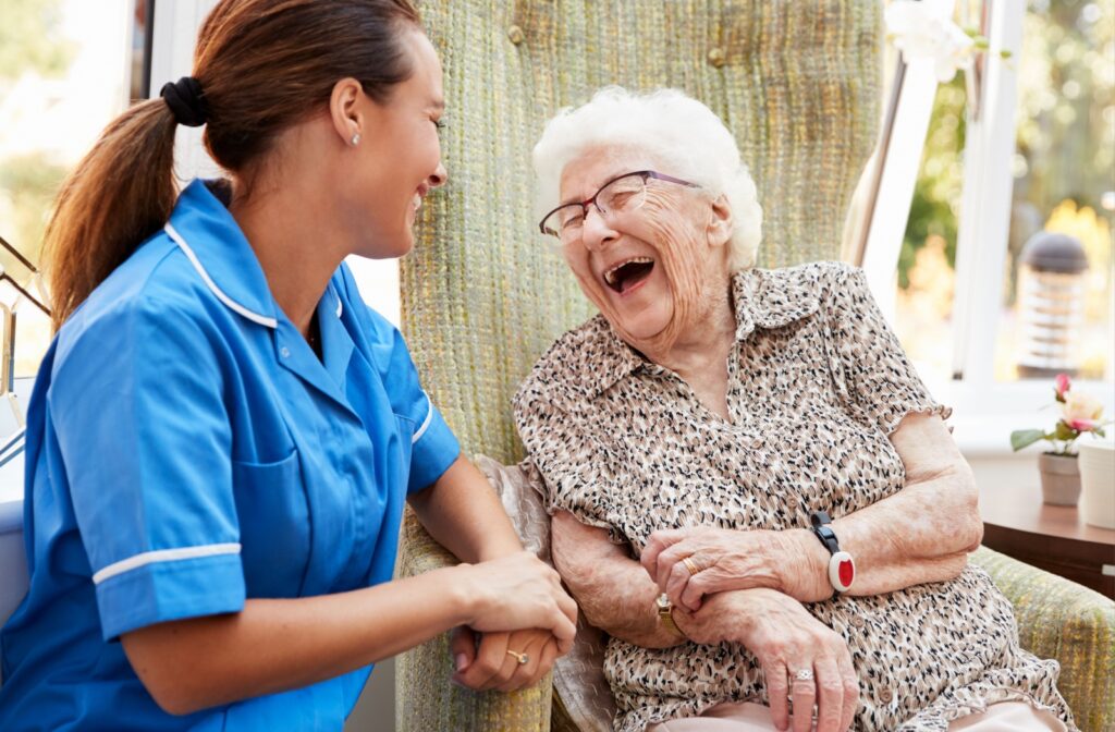 Elderly woman laughing with a caregiver.