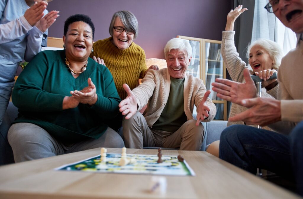 A group of older adults joyfully playing a board game together, laughing and celebrating.